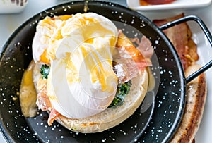 Egg benedict with bacon and sausage - delicious american breakfast