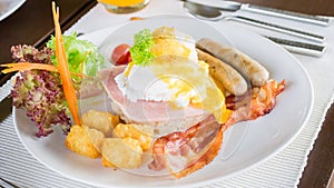 Egg benedict with bacon and sausage.