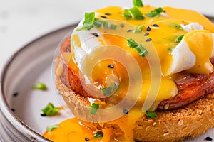 Egg benedict. Poached egg, ham, hollandaise sauce, onion on slice toast for tasty breakfast. close up