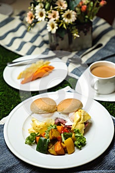 Egg Benedict slider with vegetable salad include tomato, potato, lettuce leaf and carrot with tea, coffee, and sweet melon served
