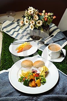 Egg Benedict slider with vegetable salad include tomato, potato, lettuce leaf and carrot with tea, coffee, and sweet melon served