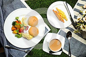 Egg Benedict slider with vegetable salad include tomato, potato, lettuce leaf and carrot with tea, coffee, and sweet melon served