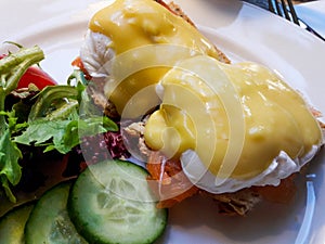 Egg Benedicts with Salmon served with cucumber and salad.