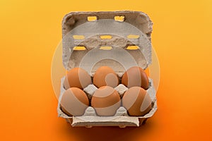 Egg box with eggs solated on yellow orange background