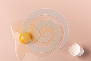 The egg is broken on a delicate pink background.