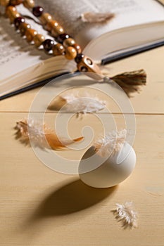 Egg, chicken feathers and bible with rosary