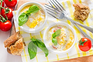 Egg cocotte in white ramekin with tomato and basil