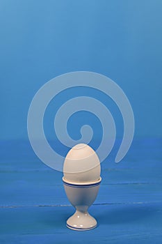 an egg in an egg cup. on a blue background.