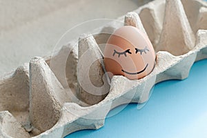 An egg with drawn emotions of happiness and pacification in an box