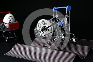Egg with drawn scared face in shopping cart stunting on black background photo