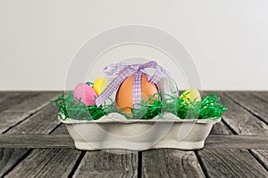 Egg in a easter nest with small eggs on a table.