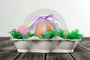 Egg in a easter nest with small eggs on a table.