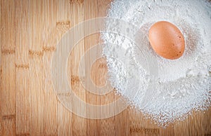 Egg with flour in kitchen on wood table, background for patisserie or kitchen