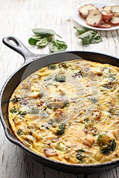Egg frittata baked in cast iron skillet with a plate of potatoes