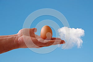 Egg in hand on sky background