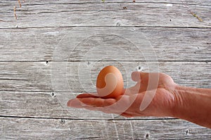 Egg in hand on wooden background