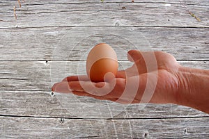 Egg in hand on wooden background