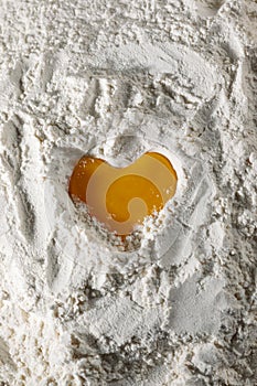 Egg heart on flour. I love to bake! Close-up of yolk on flour in the shape of a heart, full frame