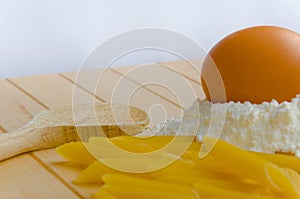 Egg lying on flour with home made penne and wooden spoon