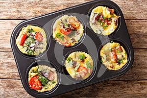 Egg muffins omelet with bacon, tomatoes, spinach and mushrooms close-up in a baking dish. Horizontal top view