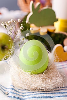 An egg in a nest with elements of floristry - elements of the Easter festive table, an option for serving.