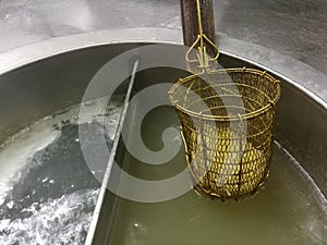 Egg noodle are cooking in hot boil water pot in chinesse restaurant with blur background, egg noodle in Scoop Colander in shop photo