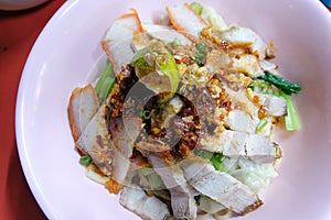 Egg noodle hot and sour soup with red roasted pork and crispy belly pork, Thailand street food.