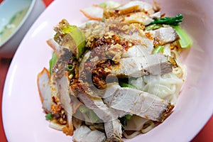 Egg noodle hot and sour soup with red roasted pork and crispy belly pork, Thailand street food.