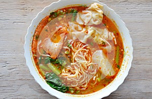 Egg noodle with pork dumpling in spicy soup on bowl