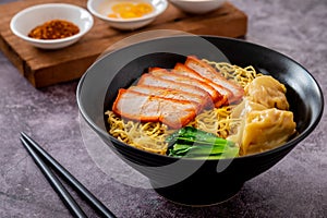 Egg noodle with red roasted pork and wonton in black bowl