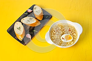 Egg noodles on a yellow background, bread and garlic on a wooden board