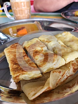 Egg paratha or Roti telur with gravy in a metal plate.