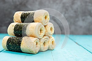 Egg rolls with seaweed stack up on blue