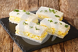 Egg salad tucked between slices of white bread, Japanese egg sandwich Tamago Sando close-up on a slate board. Horizontal photo