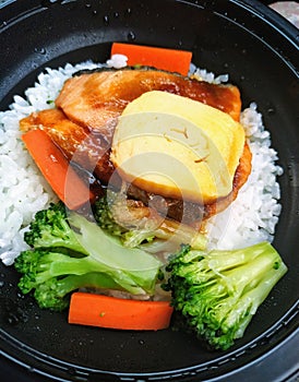 Egg salmon and vegetables hot meal in the black bowl serve for urgently time Thailand photo