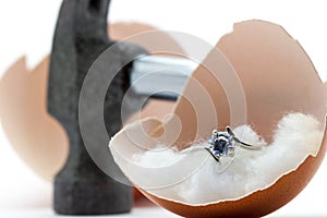 Egg shell is broken by a hammer and fake diamond ring in the egg shell.
