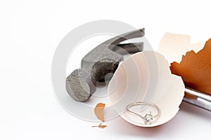 Egg shell is broken by a hammer and fake diamond ring in the egg shell.