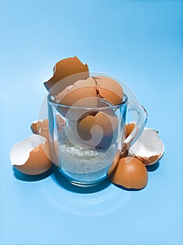 Egg Shells and Raw Rice in a transparent glass on a blue background