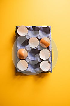 Egg shells and whole eggs in a carton. Top view