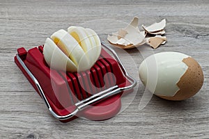 Egg slicer tool with boiled egg on wooden table