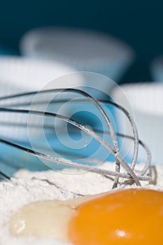 Egg and wire whisk with cupcake holders background