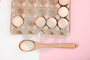 Egg on a wooden spoon. A tray of eggs on a white and pink background. eco tray with testicles. minimalistic trend, top view. Egg