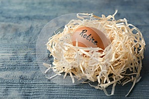 Egg with word RETIRE in nest on wooden background