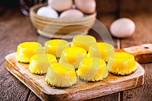 Egg yolk candy, called Quindim in Brazil, and Portugal in brisa-do-Lis. Sweet dessert on rustic wooden background photo