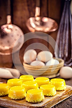 Egg yolk candy, called Quindim in Brazil, and Portugal in brisa-do-Lis. Sweet dessert on rustic wooden background photo