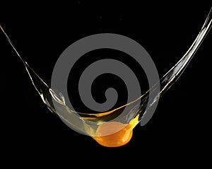 Egg yolk dripping, falling on black background.