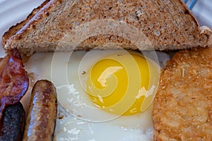 Egg yolk with sausages, bacon and toast for breakfast