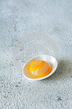 Egg yolk in a white bowl on a gray background. Egg.