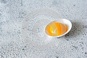 Egg yolk in a white bowl on a gray background. Egg.