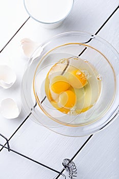 Egg yolks in a glass bowl on white wooden background